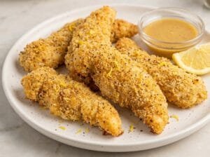 Baked Lemon Pepper Chicken Strips (Crispy, Healthy & 30 Minutes to Make) 3 Golden baked lemon pepper chicken strips with visible breadcrumb crust